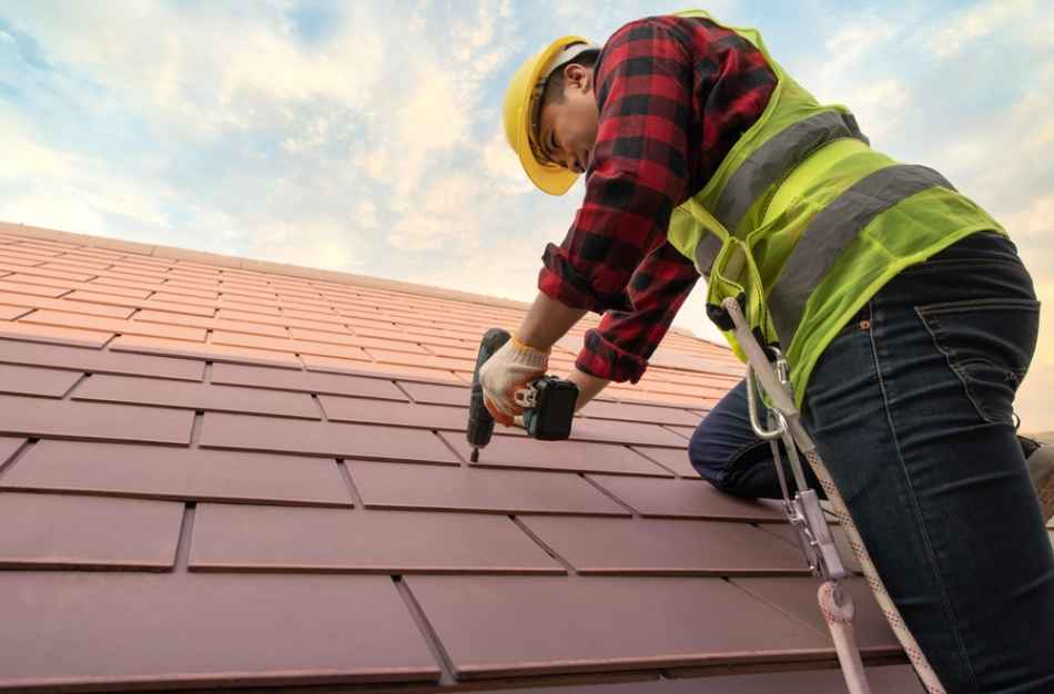 roof repair tech inspecting tile roof with drill