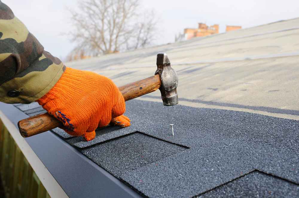 roof tech about to drive in a nail on the roof