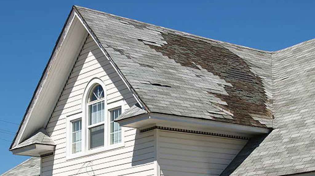 Storm-damaged shingle roof awaiting repair