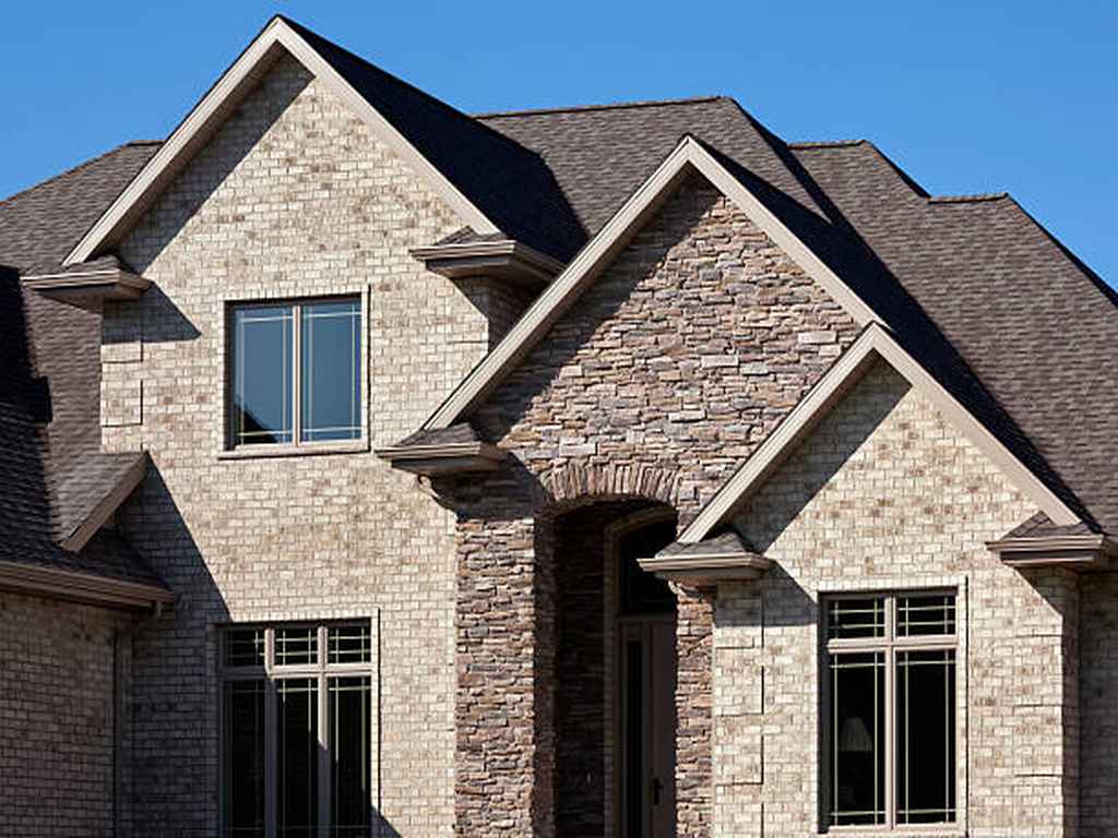 residential home with stone outside and dark shingle roof