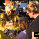 Team member in a Bowser costume hands candy to a child at the Kinetic Kids Halloween Family Unite Night in Helotes.
