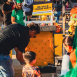 Kids in Halloween costumes play a Rhino Roofers plinko game at the Kinetic Kids Family Unite Night in Helotes, Texas.
