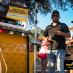 Rhino Roofers team member standing by the booth at the Kinetic Kids Family Unite Night, engaging with families in Helotes.