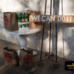Canned food donations with a “We Can Do It” sign supporting community giving at the Kinetic Kids Family Unite Night in Helotes.