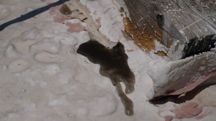 Water discharging from a roof blister on a commercial roof